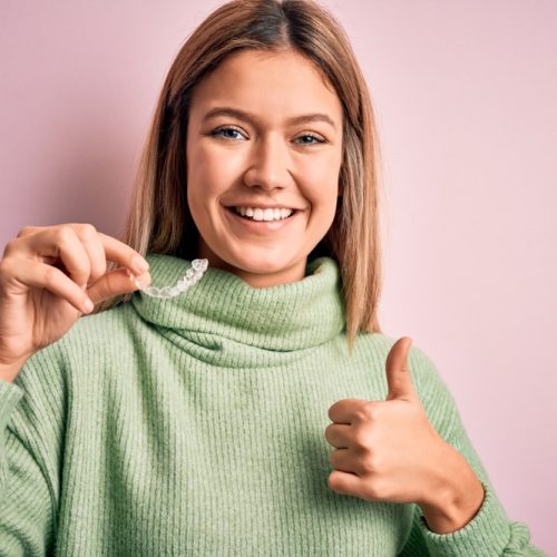 Young,Beautiful,Woman,Holding,Aligner,Standing,Over,Isolated,Pink,Background